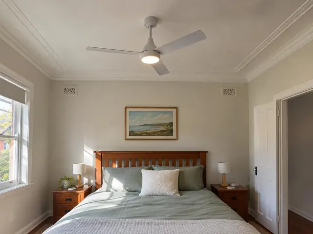 Ceiling fan with light in a bedroom with a timber bed and cream walls in Wallsend